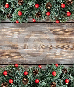 Christmas decorations with fir branches, red balls and cones on wooden background. Flat lay, top view, copy space