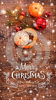 Christmas decorations with fir tree branch and tangerines on wooden background with snow, blurred