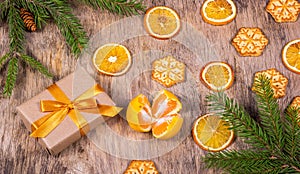Christmas decorations with fir tree, gift box, cookies, snowflakes and tangerine. Gift box with golden bow.