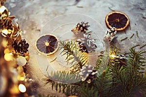 Christmas decorations with garland lights, pine cones and fir tree branch on a dark background