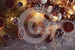 Christmas decorations with garland lights, pine cones and fir tree branch on a dark background