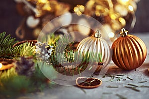 Christmas decorations with golden balls, fir tree branch and garland lights on a dark background