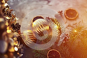 Christmas decorations with golden balls, fir tree branch and garland lights on a dark background