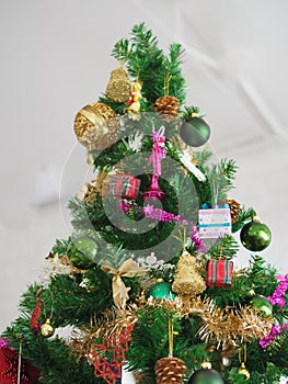 Christmas decorations green tree hanging, gold Gift box, green ball, brown Pine cones, socks, footwear, pink bell wrapped around