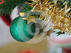 Christmas decorations green tree hanging, green ball, socks, footwear, pink bell wrapped around it with a gold ribbon on white