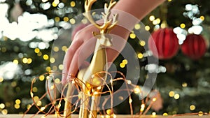 Christmas decorations. hand places a figurine of a Christmas deer on a wooden table with garlands.Decorating your home