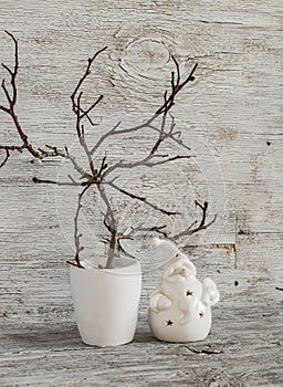 Christmas decorations home interior - dry branches in a white vase and a ceramic Santa Claus on a white wooden table