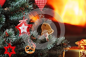 Christmas decorations hung on the tree. Blazing fireplace in the background
