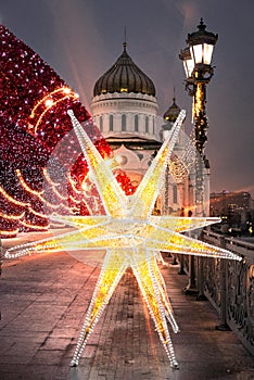 Christmas decorations on the Patriarch`s bridge on the background of the Cathedral of Christ the Savior in Moscow.