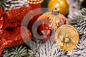 Christmas decorations, red balls and golden souvenir crypto currency Bitcoin on decorative New Year tree branch