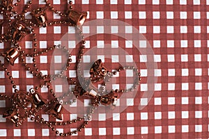 Christmas decorations: red bells garland on red and white checkered background.