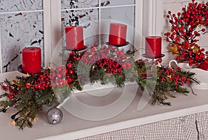 Christmas decorations with red candles and pine branch in white interior