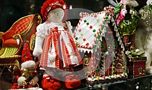Christmas decorations in toy shop window including traditional red ragdoll and Gingerbread house
