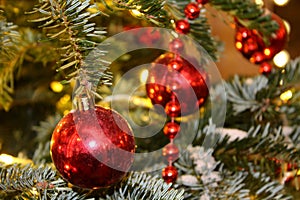 Christmas decorations on the Christmas tree in red and gold colors strewn with lights, close-up.