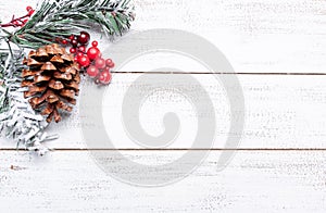 Christmas decorations on a white wood background with copy space. Pine cones, garland, berries and pine branches