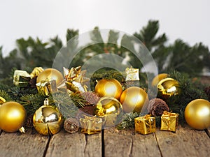 Christmas decorations yellow balls, fir branches on a wooden background with copy space. Gold style.