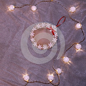 A Christmas decorative ball made of craft paper and decorated with snowflakes lies surrounded by a garland of white balls. Christm
