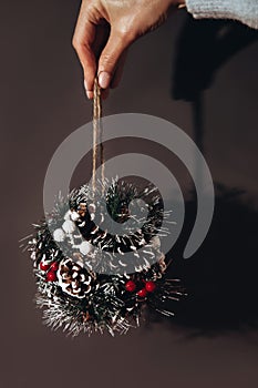 Christmas decorative ball made of fir branches and decorations in the girl& x27;s hand