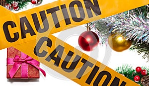 Christmas decorative pine twigs, fir branch with colorful balls, and a red gift box in the background. Yellow caution tape