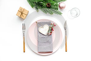 Christmas dinner decoration with gift box, plate and fir tree white table background top view