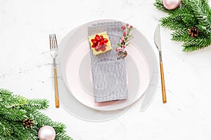 Christmas dinner decoration with gift box, plate and fir tree white table background top view