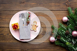 Christmas dinner decoration with gift box, plate and fir tree wooden table background top view