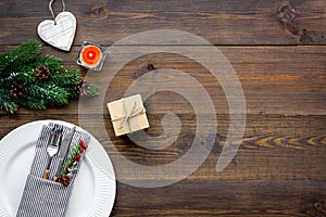 Christmas dinner decoration with gift box, plate and fir tree wooden table background top view mock-up