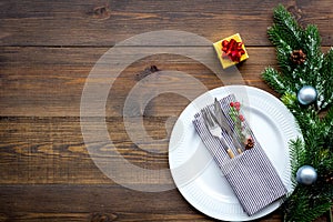 Christmas dinner decoration with gift box, plate and fir tree wooden table background top view mock-up
