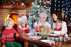 Christmas dinner. Family with kids at Xmas tree.