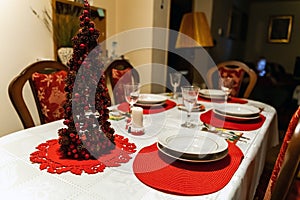 Christmas dinner feast. A decorated dining table with champagne wine glasses and christmas tree during Xmas celebration inside a