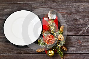 Christmas dinner. Holiday Table place settings. Christmas branches with white empty plate,red napkin and cutlery on wooden backgro