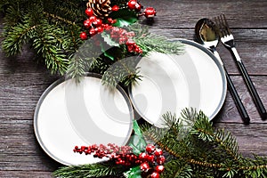 Christmas dinner. Holiday table place settings. Christmas fir branches with white empty plates.