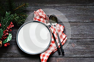 Christmas dinner plate decoration with Christmas ornaments on wood background.