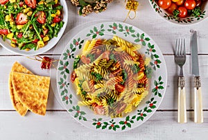 Christmas dinner table with color rotini pasta, salad. Holiday concept