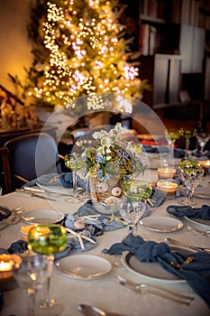 Christmas dinner table and lit Christmas tree