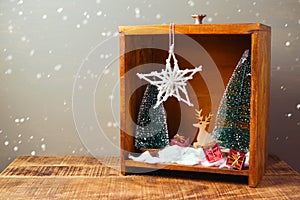 Christmas diorama with pine trees and decorations on wooden table