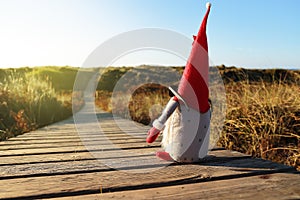 Christmas doll with sunglasses accessing the beach on a wooden boardwalk on a sunny day. Concept of Christmas, rest and vacations