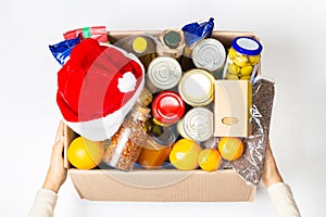 Christmas donation. Food donations box with grocery products on white background. Top view