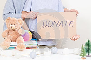 Christmas donation, holiday charity concept. Kid and woman hands holding brown piece of cardboard with inscription