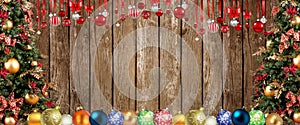 Christmas double border of ornaments, branches and buffalo plaid check ribbon. Overhead view on an old wood banner background