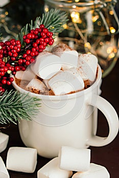 Christmas drink hot chocolate with marshmallows at festive illuminated decoration. Selective focus