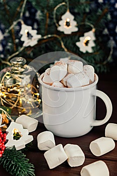 Christmas drink hot chocolate with marshmallows at festive illuminated decoration. Selective focus