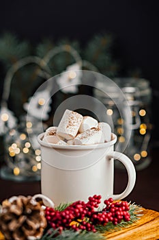 Christmas drink hot chocolate with marshmallows at festive illuminated decoration. Selective focus