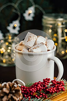 Christmas drink hot chocolate with marshmallows at festive illuminated decoration. Selective focus