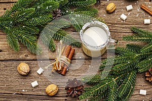 Christmas eggnog liqueur or cola de mono cocktail. Classical winter drink in glass mug, xmas decorations. Evergreen branches,