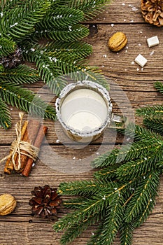 Christmas eggnog liqueur or cola de mono cocktail. Classical winter drink in glass mug, xmas decorations. Evergreen branches,