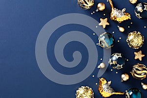 Christmas elegant navy blue background with golden Xmas balls ornaments. Stylish flat lay of festive decorations, glittering