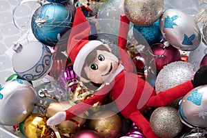 Christmas elf being naughty playing in a ball pond of christmas baubles