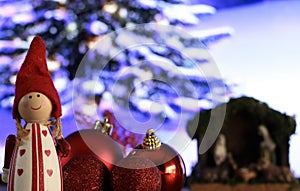 duendecillo navideÃ±o con gorrito rojo rodeado de bolas de navidad rojas y portal de belen. photo