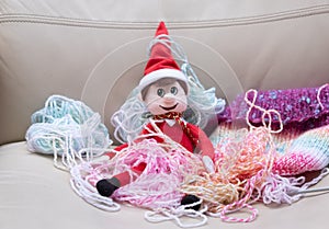 Christmas Elf mischief, naughty elf makes mess with knitting wool. Typical bad behaviour from toy elf